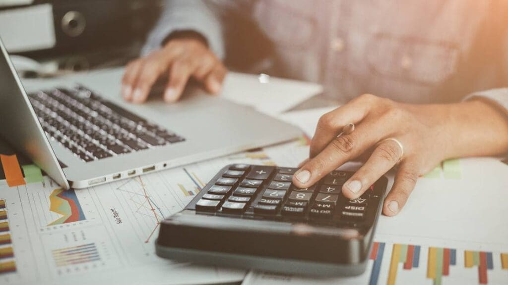 A person using a calculator and laptop
