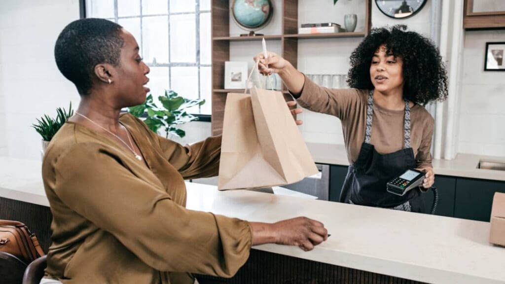 A clerk handing over a shopping bag to a customer