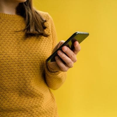 A girl dressed in yellow, holding a phone